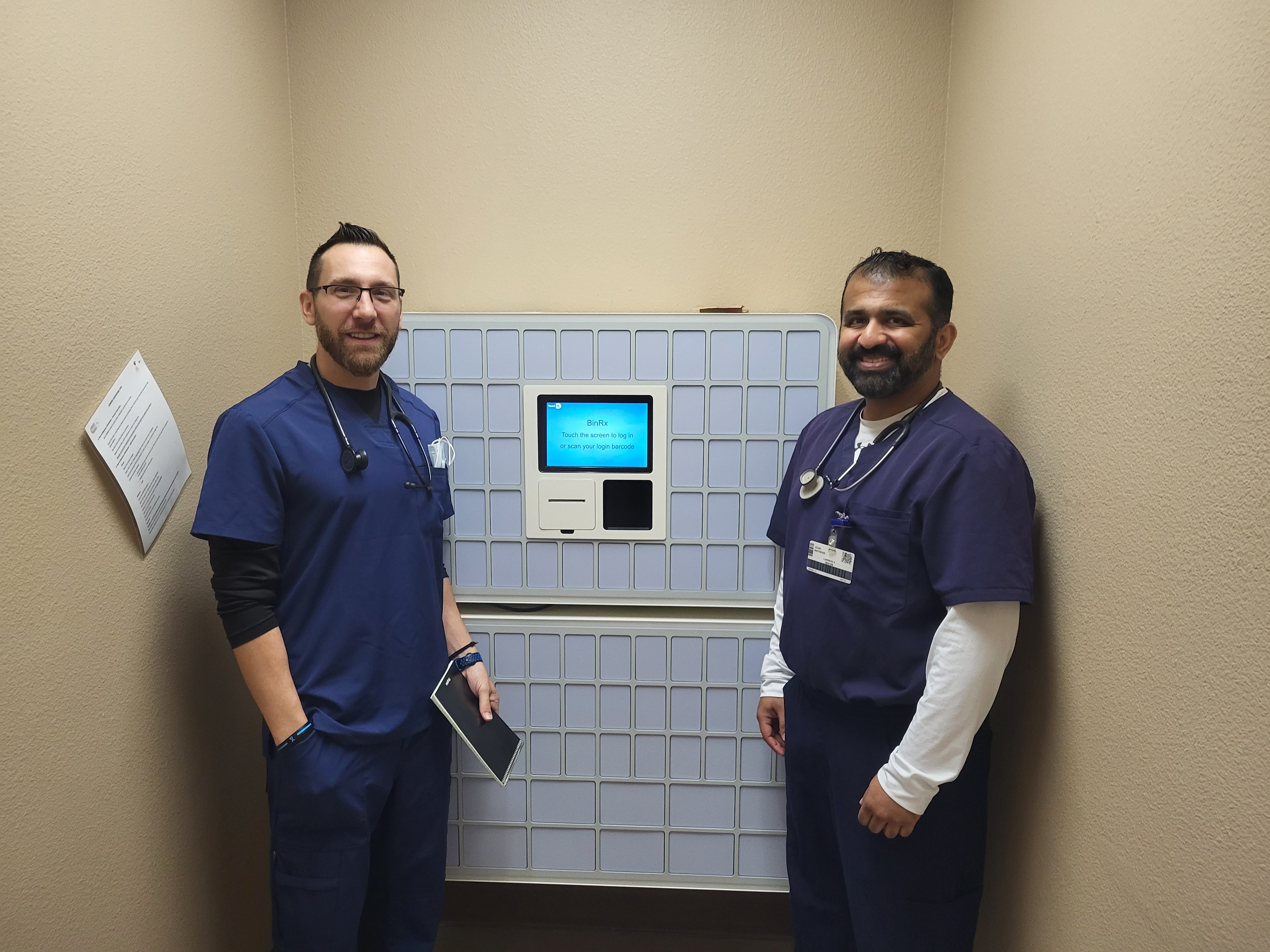 Two clinicians standing next to an in-clinic dispensing unit in a real deployment